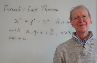 Andrew Wiles, smiling, standing in front of the statement of Fermat's Last Theorem,  in May 2023 (Image courtesy of the INI)