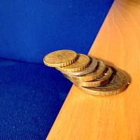 Stack of coins leaning over an edge