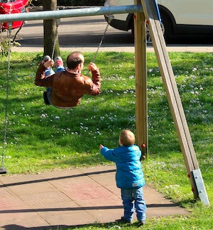 Boy pushing man on a swing