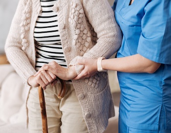 A nurse helping an elderly person stand, an example of the close physical contact required in providing care in a care home