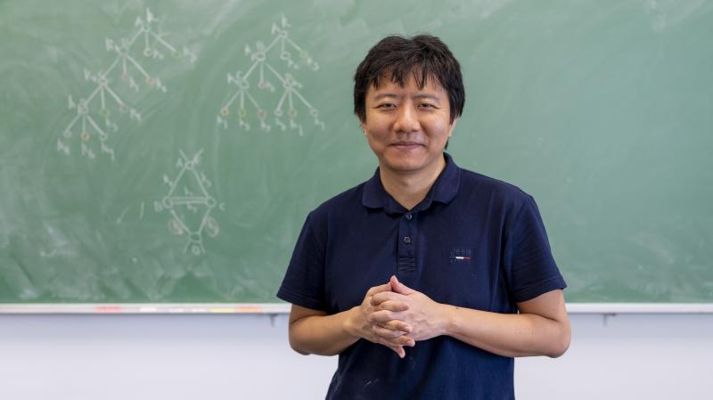 Yu Deng in front of a blackboard