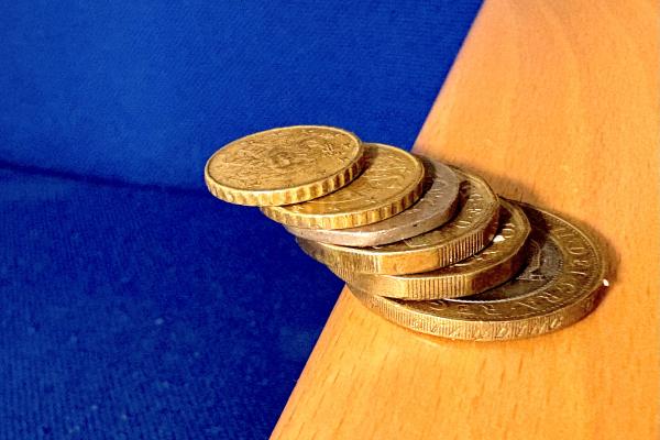 Stack of coins leaning over an edge