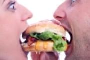 Two people each taking a bite of a burger
